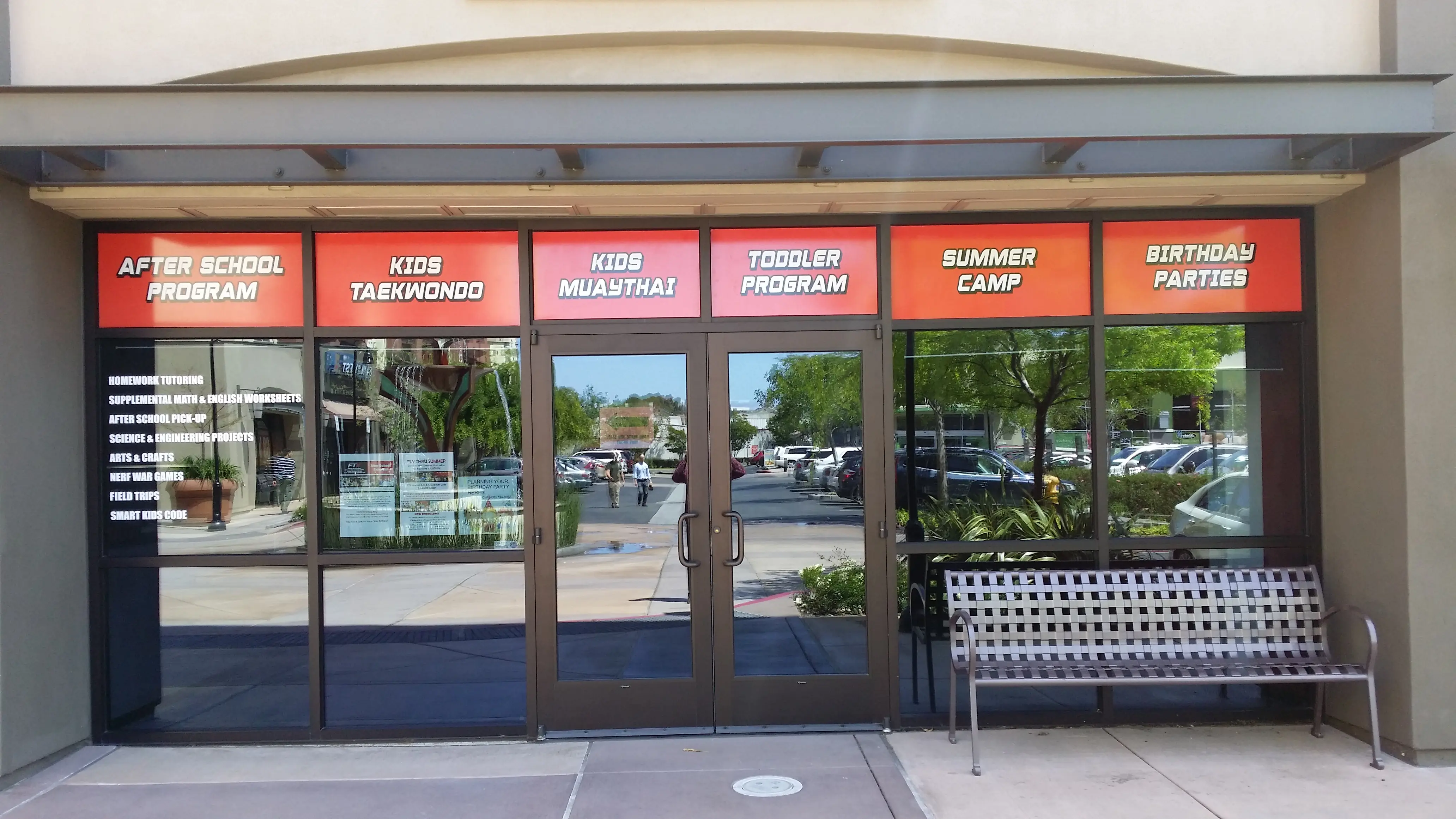 Full storefront window graphics for a martial arts studio showing programs and services