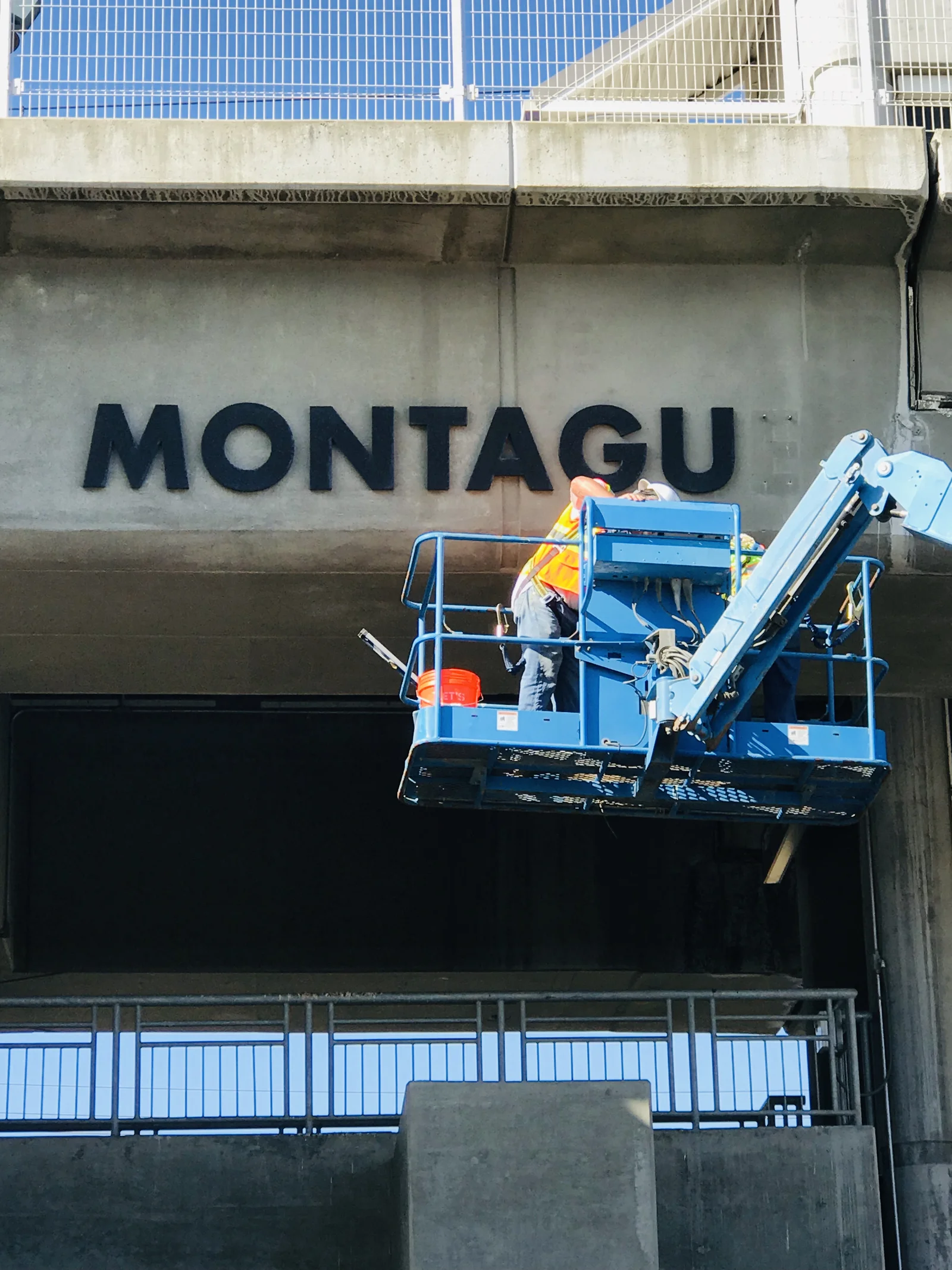 Installing dimensional letters on VTA Milpitas BART station concrete structure using boom lift
